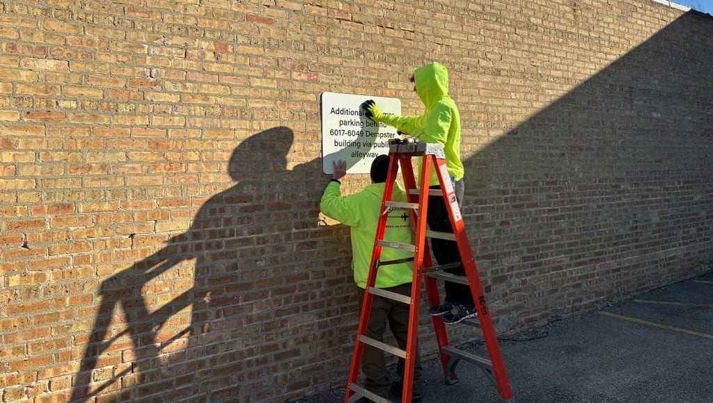 close-up of two g-force employees installing signage
