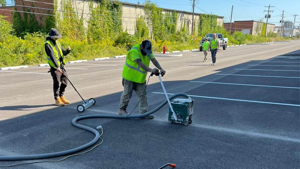 close-up of employee using line striping machine on Stelzer Road Warehouse parking lot