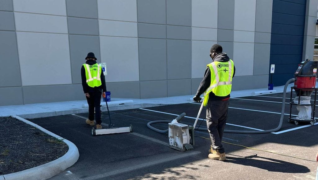 G-FORCE™ employee grinding old paint off Stelzer Road Warehouse parking lot