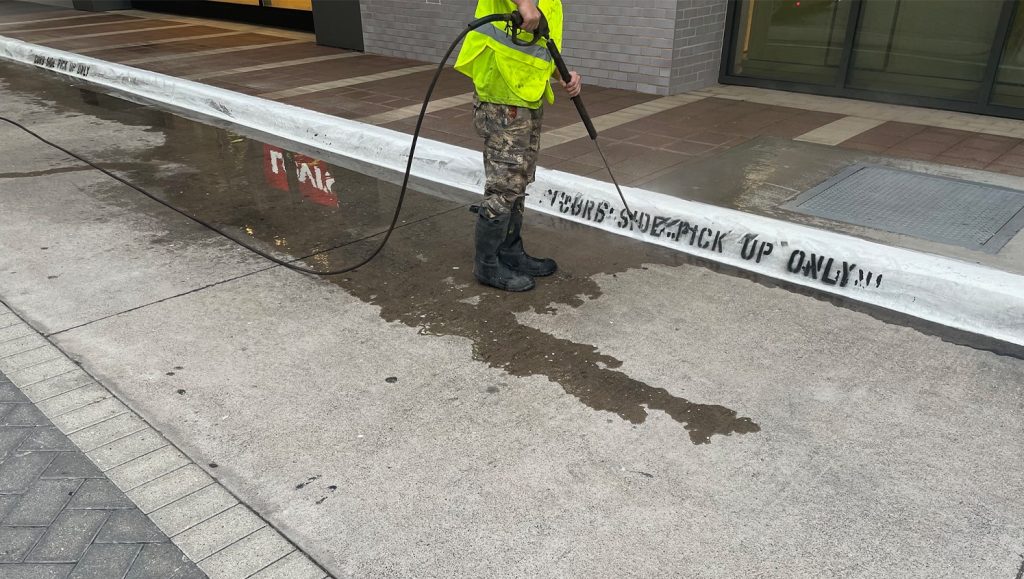 G-FORCE® employee power washing curb painting for The Shops at Legacy West