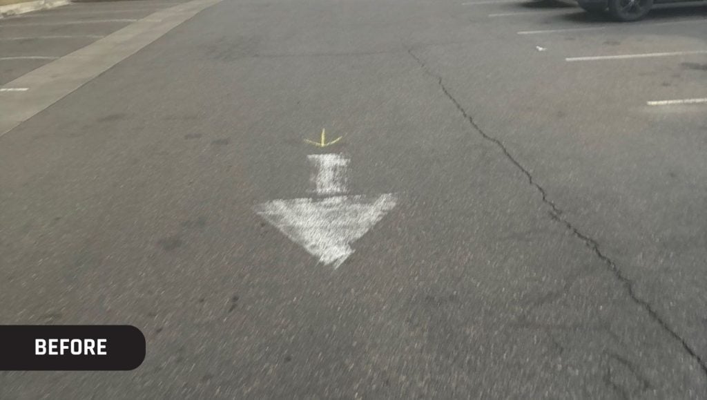 close-up of a faded white arrow on Trader Joe's parking lot
