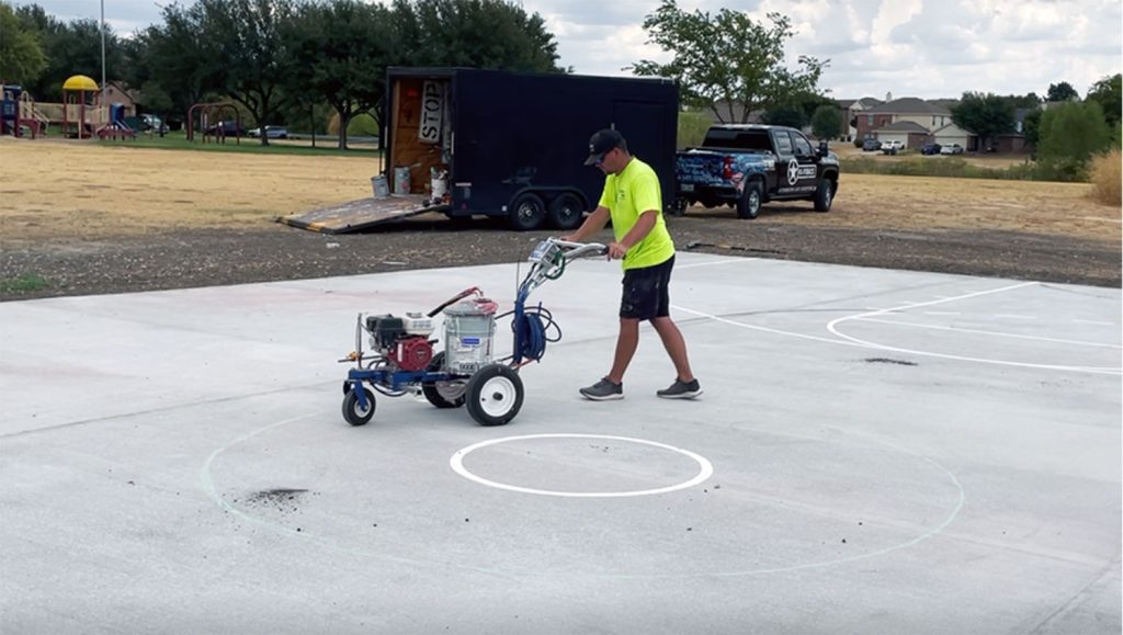 team member re-striping basketball court