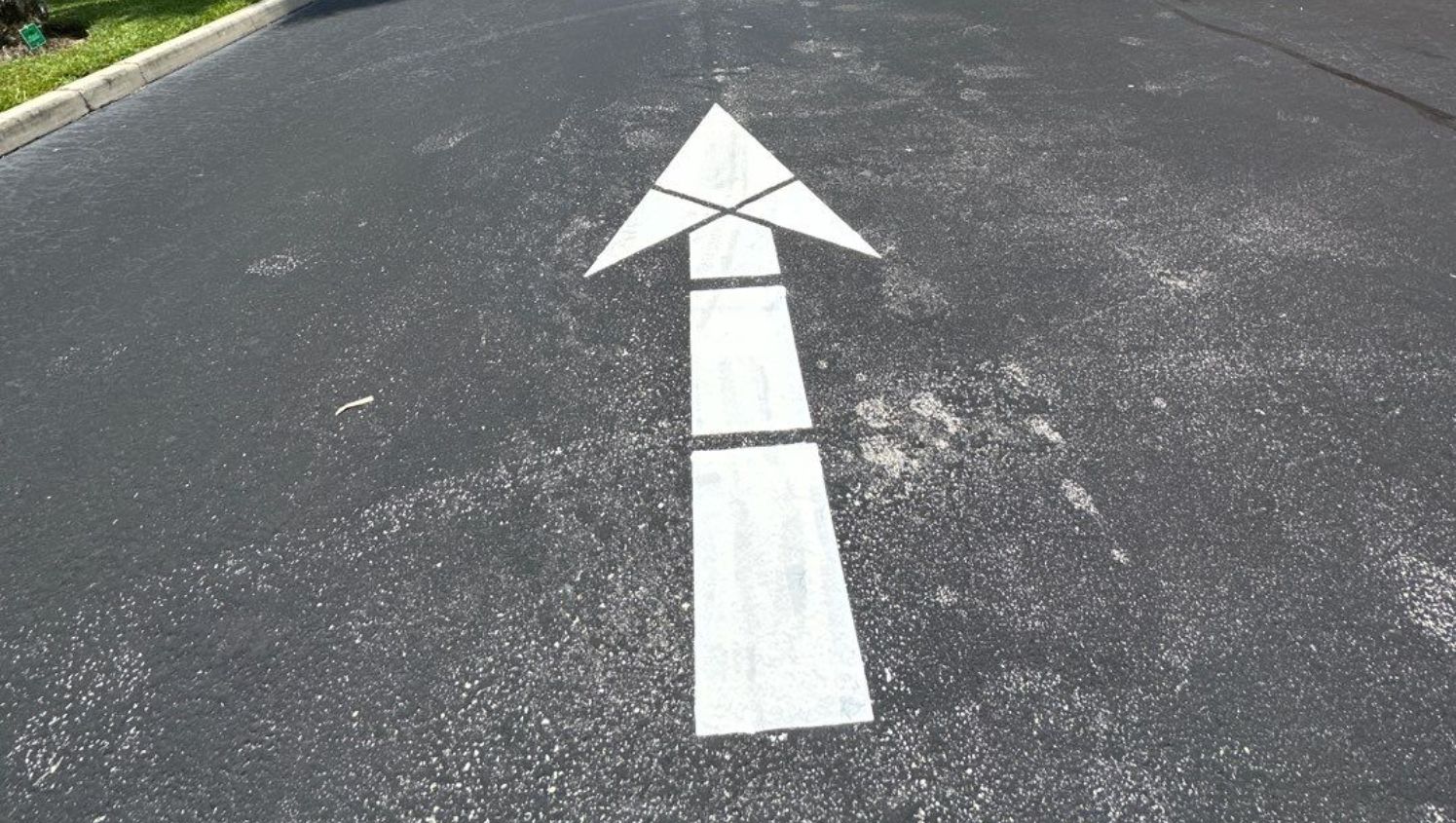 a white directional arrow on the parking lot