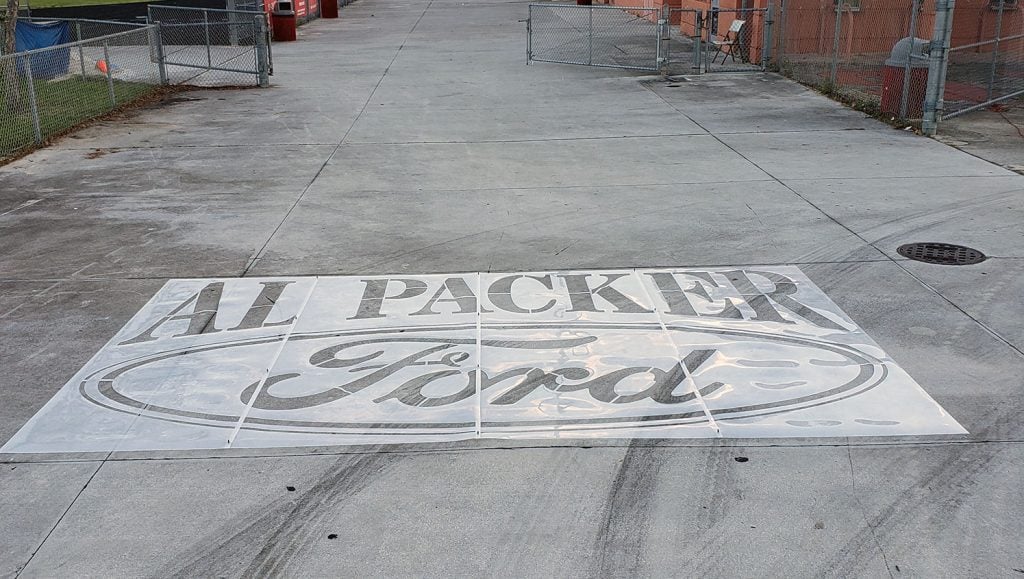 g-force worker applying paint to logo stencil