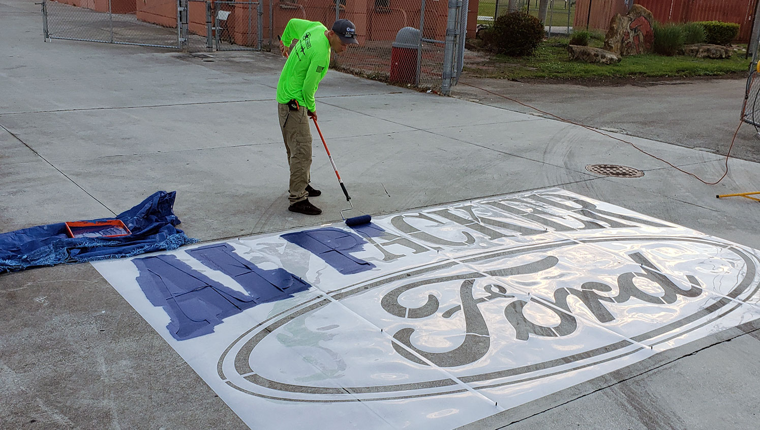 g-force worker applying paint to logo stencil