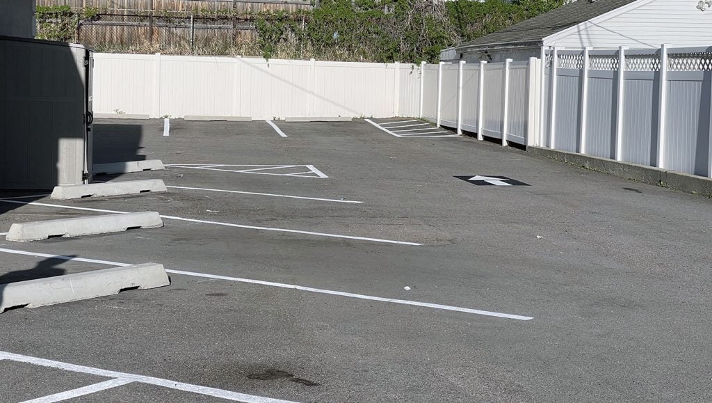 before and after photos showcasing Rising Health Specialty Clinic’s restriped parking lot