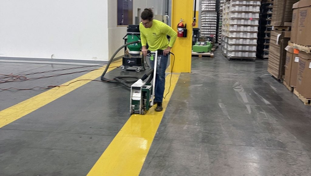 team member removing warehouse line markings
