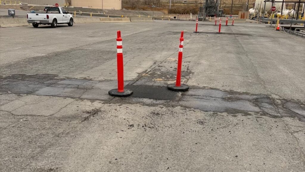 asphalt freshly poured for Chevron with cones around it