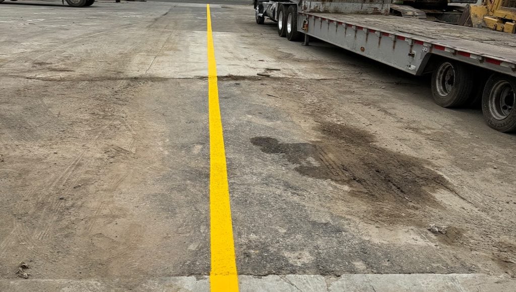close-up freshly painted yellow line marking for Trench Shoring and Reed Thomas Co. parking lot