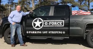jack child posing with g-force parking lot striping truck